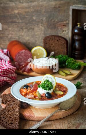 Solyanka (traditionelle russische Fleischsuppe aus verschiedenen Arten von Fleisch und Würstchen mit Gurken und Zitrone) Stockfoto