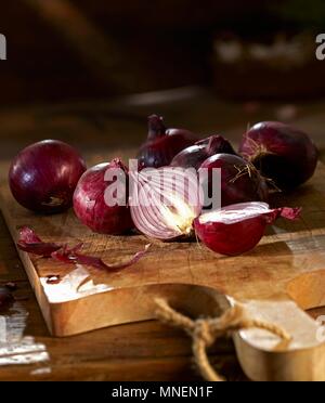 Roten Zwiebeln auf ein Schneidbrett aus Holz Stockfoto