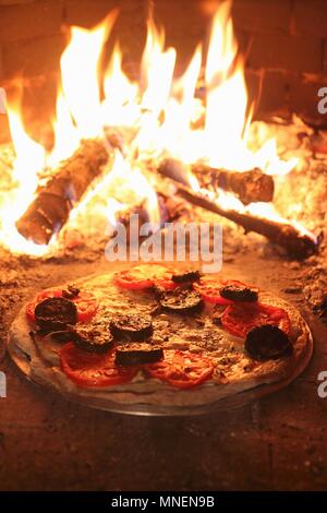 Stein - gebackene Pizza mit Käse, Tomaten und Blutwurst in einem woodfired Backofen Stockfoto