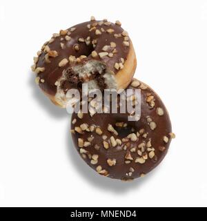 Zwei nutella Donuts mit Schokoladenglasur bestreichen und gehackte Haselnüsse, eines mit einem Bissen genommen Stockfoto