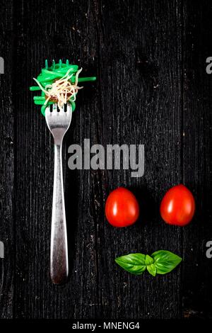 Italienische Pasta mit Tomaten und Basilikum auf Gabel auf Holzbrett Stockfoto