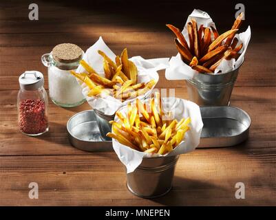 Drei Arten von Chips mit einem Salzstreuer und rosa Pfeffer auf einem rustikalen Holzmöbeln Oberfläche Stockfoto