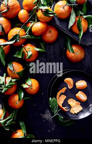 Mandarinen mit Blättern, ganz und geschält Stockfoto