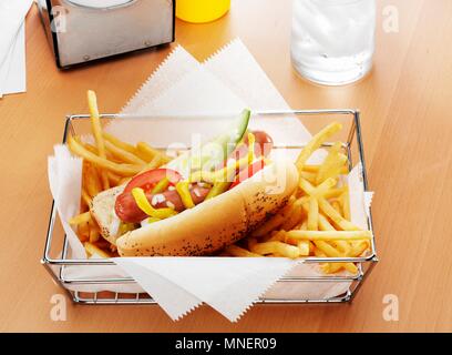 Ein Hot Dog mit den Werken und Pommes Frites in einem Metallkorb Stockfoto