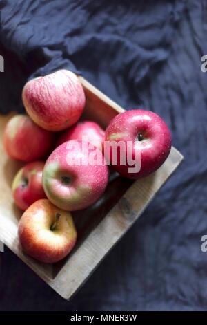 Rosa Äpfel in einer Holzkiste auf einem dunklen Grau Stoff Stockfoto