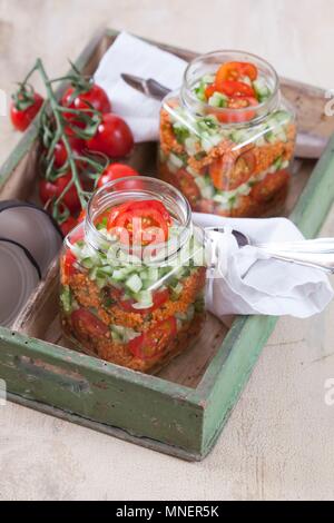 Bulgur weizen Salat mit Granatapfel Sirup, Zwiebeln, Gurken, Tomaten, Petersilie und Minze im Glas Stockfoto