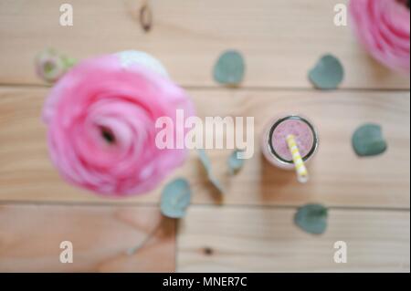 Himbeere Milch mit einem Stroh in einer Flasche und eine ranunculus Blume in einer Vase (von oben gesehen) Stockfoto