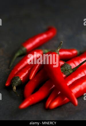 Ganze frische Birds Eye chilis auf dunklem Schiefer Hintergrund Stockfoto