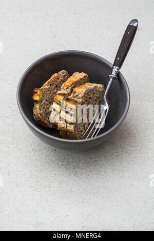 Drei Scheiben glutenfreies Bananenbrot mit Chia Samen in eine Schüssel geben. Stockfoto
