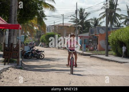 Ecuadorianischen Mädchen mit dem Fahrrad auf einem sand Straße in Puerto Villamil, Isabela Island, Galapagos, Ecuador. Stockfoto