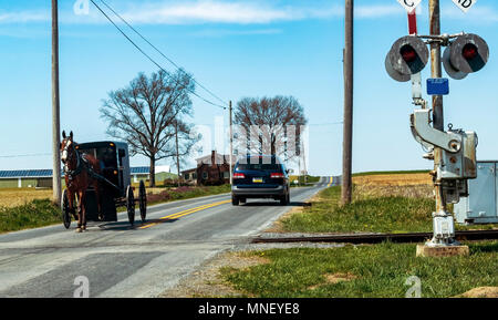 Amish Buggy vorbei an Rail Road Kreuzung an einem Frühlingstag Stockfoto