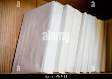 Regal in der Bibliothek, weiße Abdeckung buchen Sie für Ihre eigenen Texte füllen. Regal mit vielen Büchern. einen Stapel Bücher auf Holzregal. Selektive konzentrieren. Stockfoto