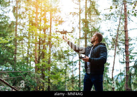 Guy startet einen quadrocopter im Wald Stockfoto