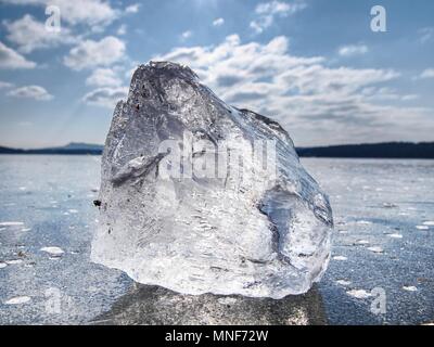 Charmante Wintersonne hiden hinter Stück Clear Ice. Leuchtendes Stück Eis liegt auf See Eis und schöne Reflexion erstellen. Stockfoto