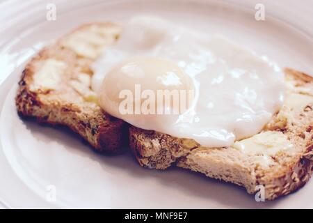 Die perfekt pochierte Eier auf Gesäte gebuttertem Toast braun-Filter angewendet Stockfoto