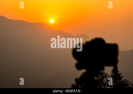 Kamera auf Stativ bereit für Aufnahmen Bild. Sonnenaufgang in den Bergen in den Morgen. Gold Licht über den Himmel. Stockfoto