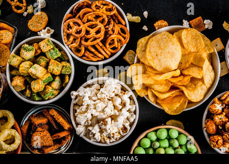Variation verschiedener ungesunden Snacks Kekse, süßes Popcorn gesalzen, Tortillas, Muttern, Strohhalme, bretsels, zurück Tafel Platz kopieren Stockfoto