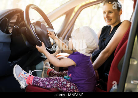 Kinder spielen im Auto Lenkrad. Süße kleine Mädchen fahren Auto
