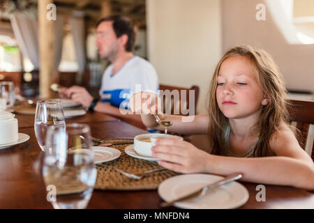 Adorable kleine Mädchen essen Frühstück im Haus oder im Restaurant Stockfoto