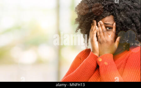 Schöne afrikanische Frau lächelnd in schüchtern schauen spähen durch ihre Finger, das Gesicht mit den Händen verwirrt im großen und ganzen suchen, Außenpool Stockfoto