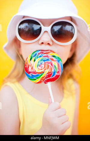 Adorable kleine Mädchen mit Lollipop über bunten Hintergrund Stockfoto