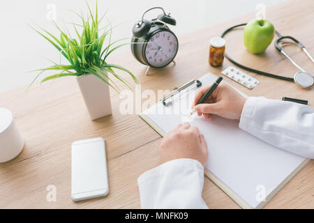 Ärztin Notizen, medizinische Geschichte des Patienten oder Medizin Rezept auf Zwischenablage Papier während der medizinischen Untersuchung im Krankenhaus Büro Stockfoto