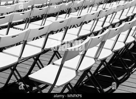 Reihen von weißen leeren Klappstühle in einem Sommer Theater. Stockfoto