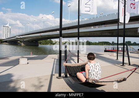 Eine junge Dame mit einem Buch in eine Hängematte am Ufer der Donau in Wien, Österreich. Stockfoto