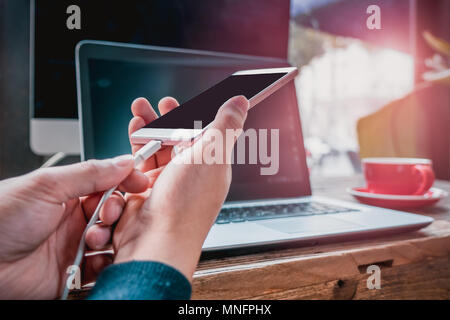 Frau Hand halten das Ladekabel anschließen des Smart Handy Stockfoto