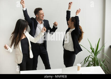 Aufgeregt und Kollegen feiern online gewinnen die Hände Stockfoto