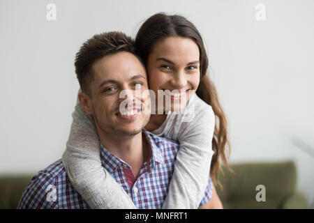 Lächelnd Mann huckepack fröhliche Frau an der Kamera auf der Suche Stockfoto