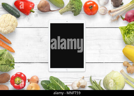 Tablet und Gemüse auf wihite Holzschreibtisch. Ansicht von oben. Stockfoto