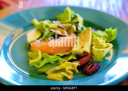 Gesund grüner Salat mit Grapefruit, Mandeln, und leichte Vinaigrette für Geschmack und Ernährung hinzugefügt. Auf schönen rot und türkis Platten gelegt. Stockfoto