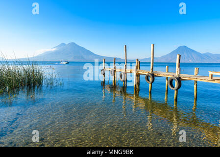 Holz- pier am Atitlan See, an der Küste bei Panajachel, Guatemala. Mit schönen Landschaft der Vulkane Toliman, Atitlán und San Pedro. Stockfoto