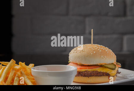 Burger auf einem Teller mit Bratkartoffeln und Sauce Stockfoto