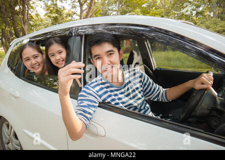 Gerne asiatische Familie auf Mini Van sind lächelnd und fahren für Reisen im Urlaub Stockfoto