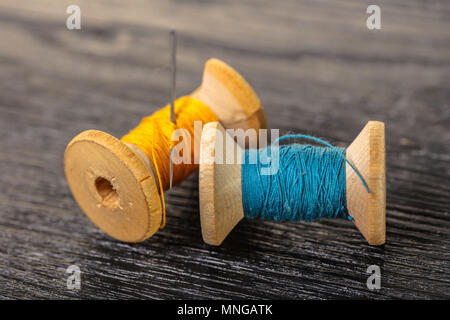 Farbigen Fäden und Nadel auf schwarzem Holz Hintergrund Stockfoto