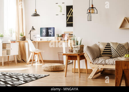 Moderne loft innen voll von natürlichen Holz- Möbel und Accessoires mit Schreibtisch, Computer, weiße Brust, beige Sofa, Tisch und Papier Töpfe für Pflanzen Stockfoto