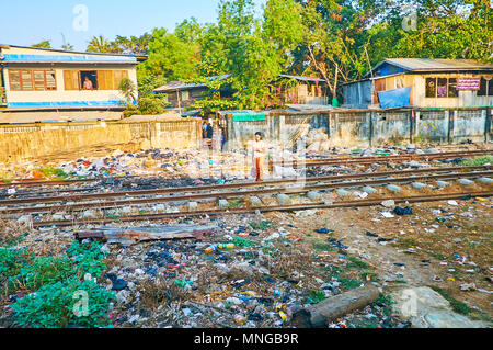 YANGON, MYANMAR - Februar 16, 2018: Das junge Mädchen die Eisenbahnen, mit Müllkippe abgedeckt Kreuze, Pa Thein Nyunt Bezirk, am 16. Februar in Yangon. Stockfoto