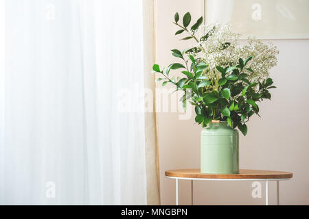 Blumen in grün Vase auf einem kleinen Holztisch Stockfoto