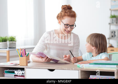 Lächelnde Mutter ihrem Sohn helfen bei den Hausaufgaben sitzen im Büro zu Hause Stockfoto