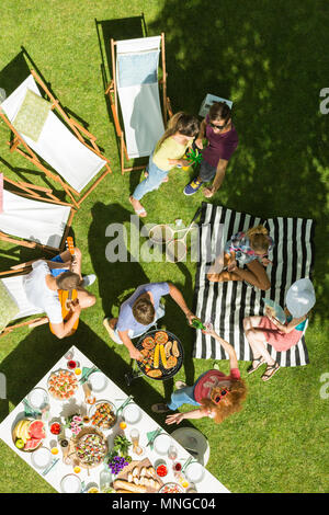 Blick von oben auf die Gruppe von Freunden mit Picknick im Garten Stockfoto