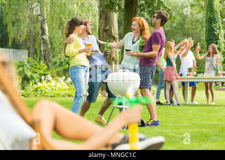 Junge Menschen Grillen und trinken in Garten Stockfoto