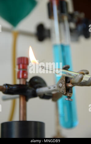 Flamme brennen aus einem Glasrohr mit Laborgeräten als diffuser Hintergrund. Stockfoto