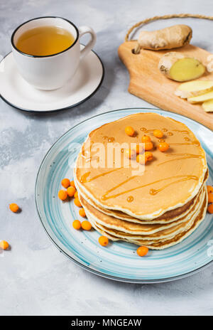 Hausgemachte Frühstück: amerikanische Pfannkuchen serviert mit Beeren und Zucker powderwith eine Tasse Tee auf konkreten Hintergrund. Stockfoto