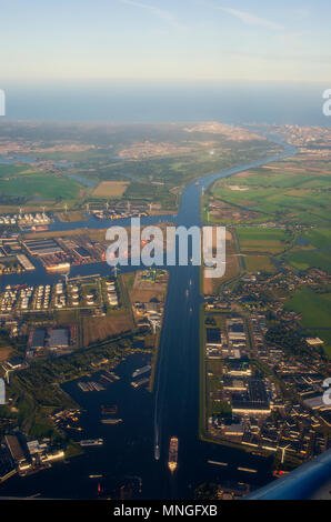 Ein Luftbild bei Sonnenuntergang von Westpoort, der Hafen von Amsterdam, Niederlande, Öltanks, Windenergieanlagen und der Nordzeecanaal. Stockfoto