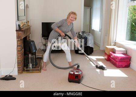 Home Umzüge, Frau mit einem Staubsauger den Teppich zu Hoover, bevor Sie aus dem Haus. Stockfoto