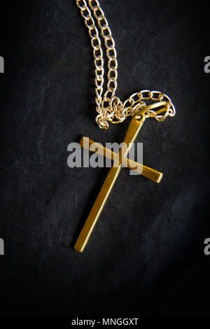 Ein einfaches Metall Kreuz auf eine Kette liegt vor schwarzem Hintergrund Stockfoto