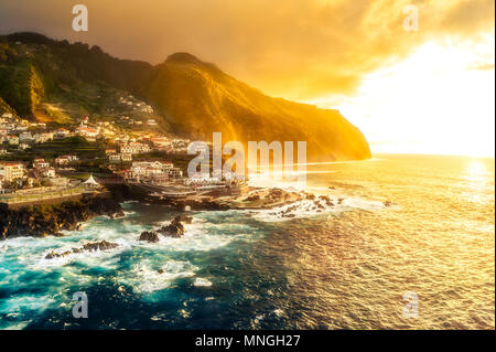 Schöne dramatische goldenen Sonnenuntergang über Küstenstadt Porto Moniz, Insel Madeira, Portugal - von oben gesehen Stockfoto