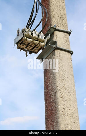 Im Alter von drei-phasige elektrische Schalter ist auf einem urigen konkrete Spalte installiert. Sonnige sprig Tag Außenaufnahme Stockfoto